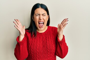 Beautiful brunette woman wearing wool winter sweater celebrating mad and crazy for success with...