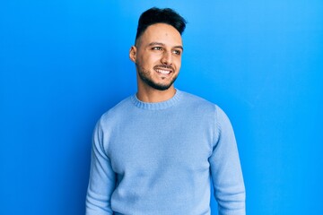 Young arab man wearing casual clothes looking to side, relax profile pose with natural face and confident smile.