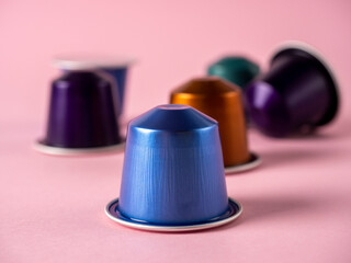 Colorful aluminum capsules with ground coffee on a paper rose background. Capsules for the coffee machine
