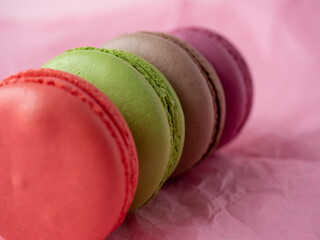 Traditional macaroon cookies of different colors lie on a pink paper background. Isolated item, sweets, confectionery. Top view