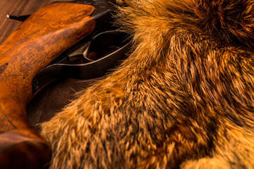 Hunting rifle lying next to the animal's fur produced. View close-up