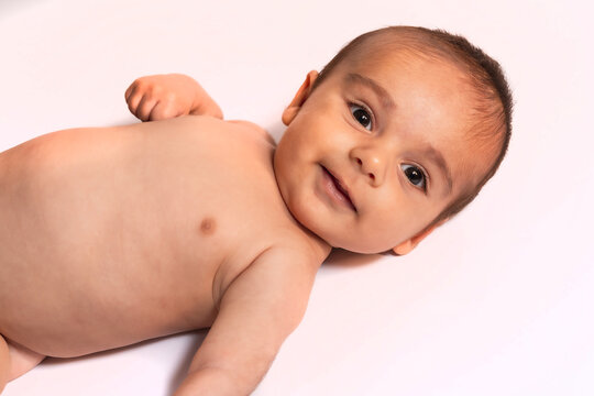 Two month old Caucasian baby lying smiling looking at camera. Studio photos with white background
