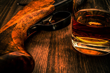 Hunting rifle and glass of whiskey close-up. Focus on the trigger of the rifle