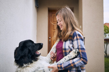 Happy teenage girl coming home and welcoming with her joyful dog (Czech mountain dog). .