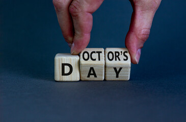 Doctor day symbol. Doctor turns wooden cubes with words 'Doctors day'. Beautiful grey background. Doctor day and medical concept. Copy space.