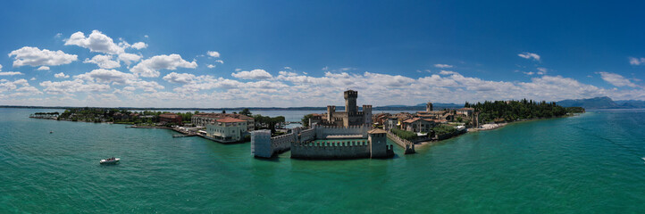 Obraz premium Aerial Panorama of the island of Sirmione. Sirmione, Lake Garda, Italy. Peninsula on a mountain lake in the background of the alps. Castle on the water in Italy.