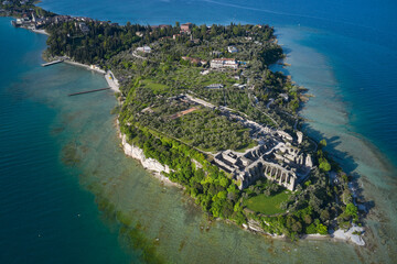 Aerial view of the Grotte di Catullo Ruins at high altitude. Grottoes ruins on the Sirmione peninsula. Olive grove and archaeological museum. Lake Garda, Italy.