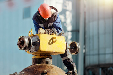 A man in work clothes and a hard hat works with gas equipment outdoors in winter. Repair of the...
