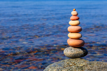 Rock zena pyramid of colorful stones on the background of the sea. Wellness concept