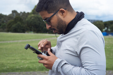 A young man piloting his drone in the park