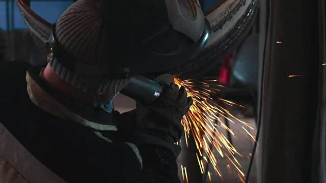 The welder processes the weld with a grinding machine and sparks fly. Processing of welded metal pipe rings. A gas industry welder is practicing the skill of welding pipes.