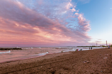 Toronto Beaches sunset with waves breaking on the sand and colorful plastic muskoka chairs in the surf, seen from Kew Beach in Toronto's east end.