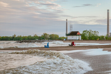 Toronto Beaches sunset with waves breaking on the sand and colorful plastic muskoka chairs in the...
