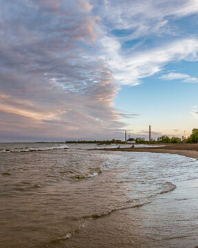 Toronto Beaches sunset with waves breaking on the sand and colorful plastic muskoka chairs in the surf, seen from Kew Beach in Toronto's east end.
