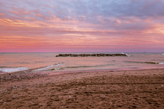 Toronto Beaches sunset with waves breking on the sand, seen from Kew Beach in Toronto's east end.