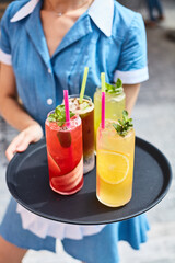 waitress holds refreshing cocktails on a tray on the terrace