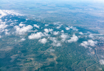 Aerial view from airplane window above grenn ground. View from the airplane window with beautiful clouds at sunrise