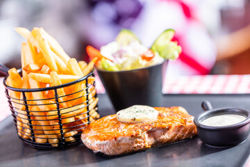 Salmon steak with salad and french fries in american restaurant
