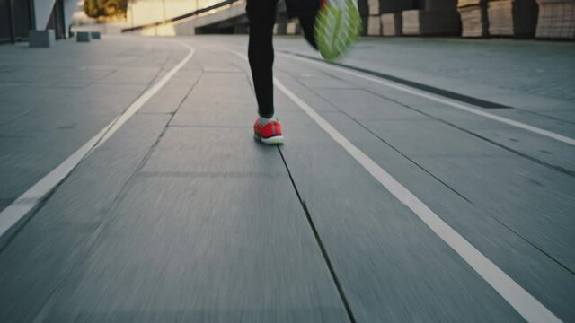 Follow shot of unrecognizable man sprinter practicing run workout at urban training court, running fastly, back view