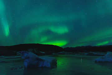 Northern Lights on the night sky. Wintertime starry sky. Aurora Borealis above blue icebergs.