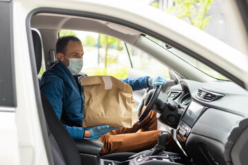 Postal delivery courier man wearing protective face mask in front of cargo van delivering package holding box due to Coronavirus disease or COVID-19