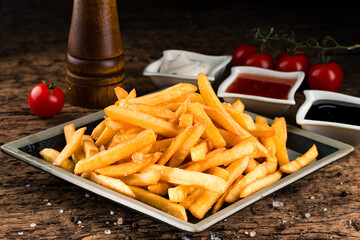 Delicious french fries and ketchup. fast unhealthy food background, closeup on wooden background