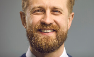Closeup portrait of happy handsome middle-aged man with thick ginger beard smiling at camera....