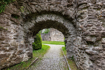 Fototapeta na wymiar old stone arch in the garden, stone walls of a castle