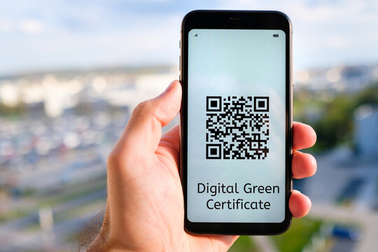 Digital Green Certificate with QR code on the screen of mobile phone in mans hand on the background of cityscape.  - Powered by Adobe