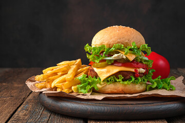 A large homemade burger and French fries on a brown background.
