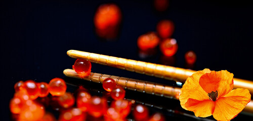 Maki - Sushi,   roter Kaviar, Stäbchen,  Blümchen, Nahaufnahme,    schwarze  Hintergrund © Nina