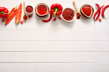 Composition with tasty chili sauce and ingredients on light wooden background