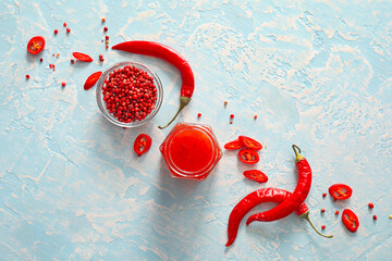 Composition with tasty chili sauce and ingredients on color background