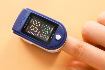 Hand with pulse oximeter on color background - obrazy, fototapety, plakaty