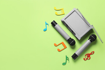 Modern microphones with audio system and music notes on color background