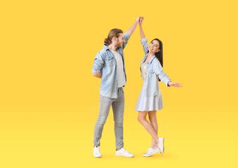 Happy young couple dancing on color background