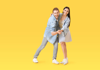 Happy young couple dancing on color background