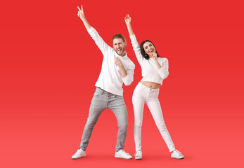 Happy young couple dancing on color background
