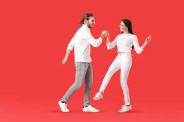 Fototapeta na wymiar Happy young couple dancing on color background