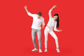 Happy young couple dancing on color background