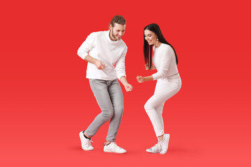 Happy young couple dancing on color background