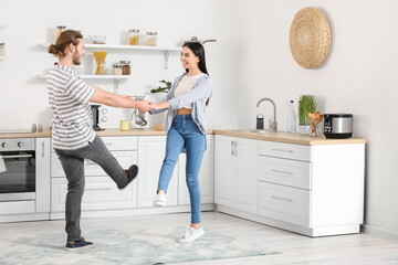 Fototapeta premium Happy young couple dancing in kitchen