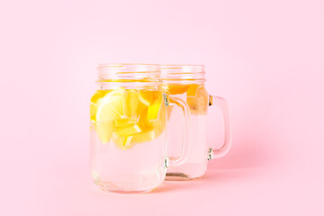 Mason jars of tasty cold lemonade on color background