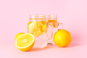 Mason jars of tasty cold lemonade on color background