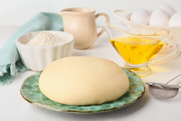 Plate with fresh dough, flour, eggs and oil on light background, closeup