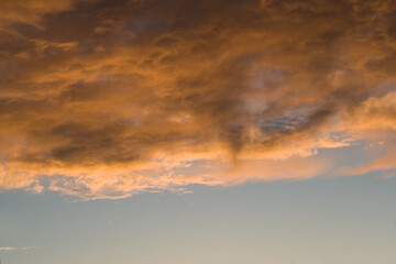 Fototapeta premium Skyscape sunset background. Colorful orange clouds on blue sky at evening