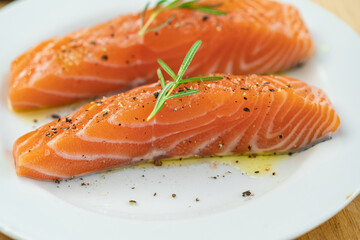 Salmon steak a piece of fresh home cooking with rosemary, olive oil, black pepper and himalayan salt on a white plate. Focus select and blur close up and Macro photography.