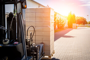 Forklift vehicle manipulating goods in logistic area outside warehouse.