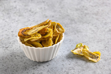 Sliced fresh and dried fruits kiwi chips on gray background, home drying. Snack vegan free sugar...