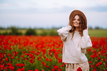 Young woman walking in amazing poppy field. Summertime. Beautiful woman posing in the blooming poppy field. Nature, vacation, relax and lifestyle.